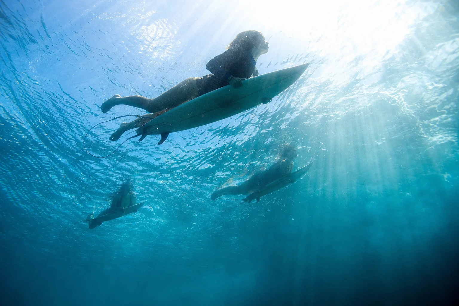 Underwater view of two surfers paddling